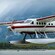 A floatplane lands on a river with a misty mountain in the background